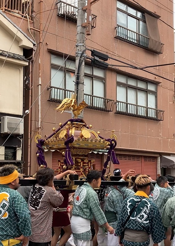 玉姫稲荷神社の祭礼で、昼間に神輿を担ぐ氏子たち。背景は下町の住宅街