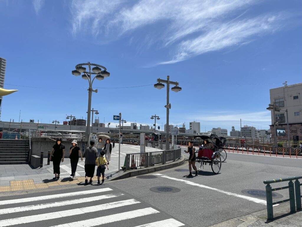 吾妻橋のたもとの交差点。観光客が歩いており、人力車が走っている風景。