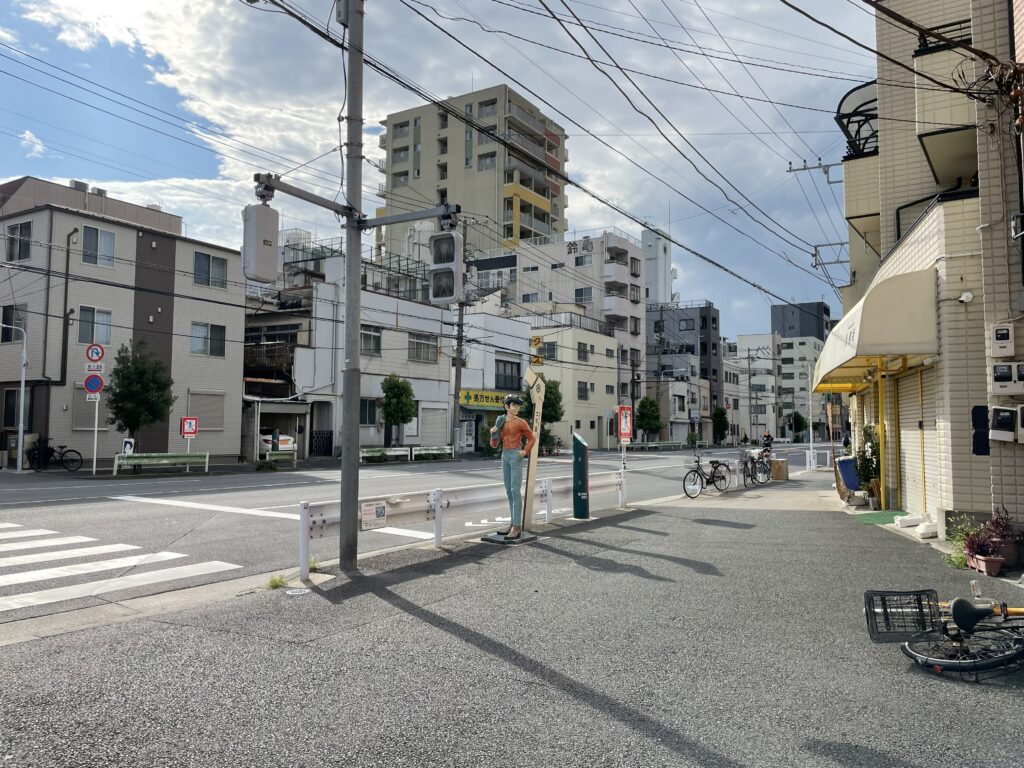 土手通り沿いの歩道に設置された明日のジョーの銅像と周囲の街並み