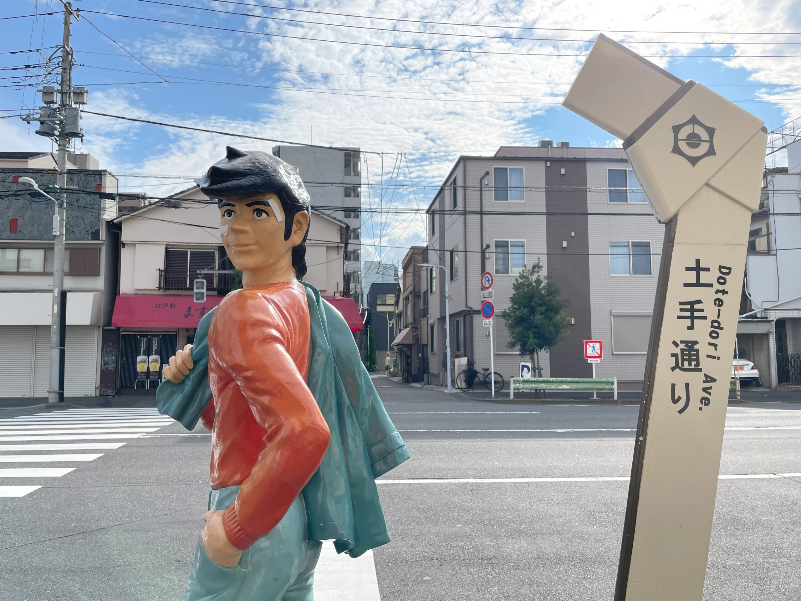 振り返るポーズの明日のジョー像と「土手通り」と書かれた標識