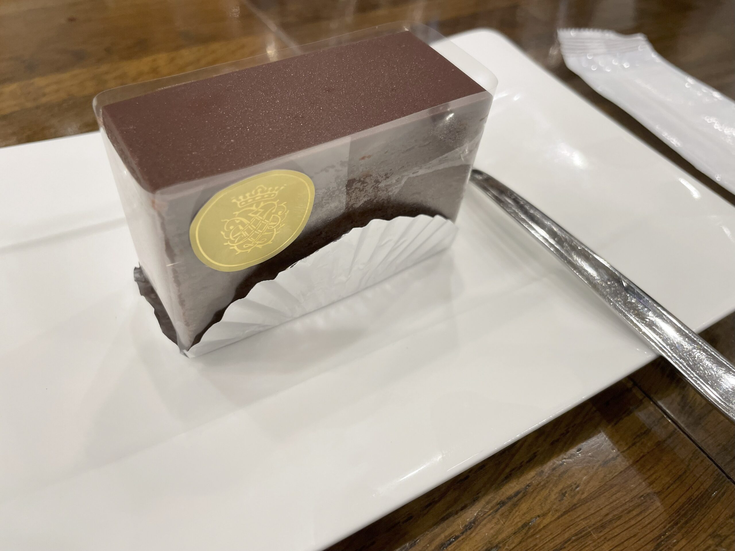 白い皿の上に、チョコレートケーキとフォークが置かれている。