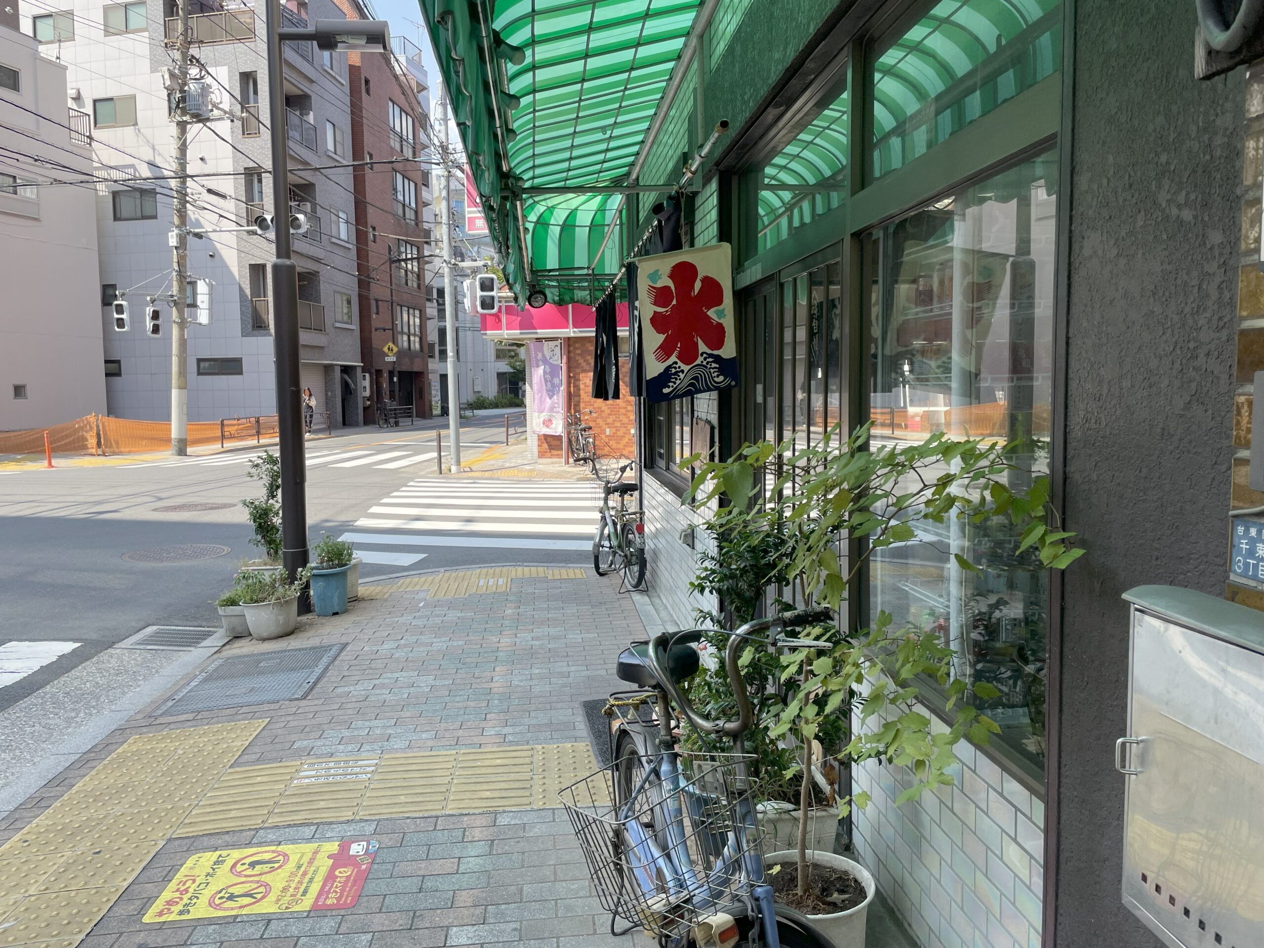店舗外観。緑のテントの下に「氷」と描かれた旗が下がり、入り口前に植木鉢が並んでいる。