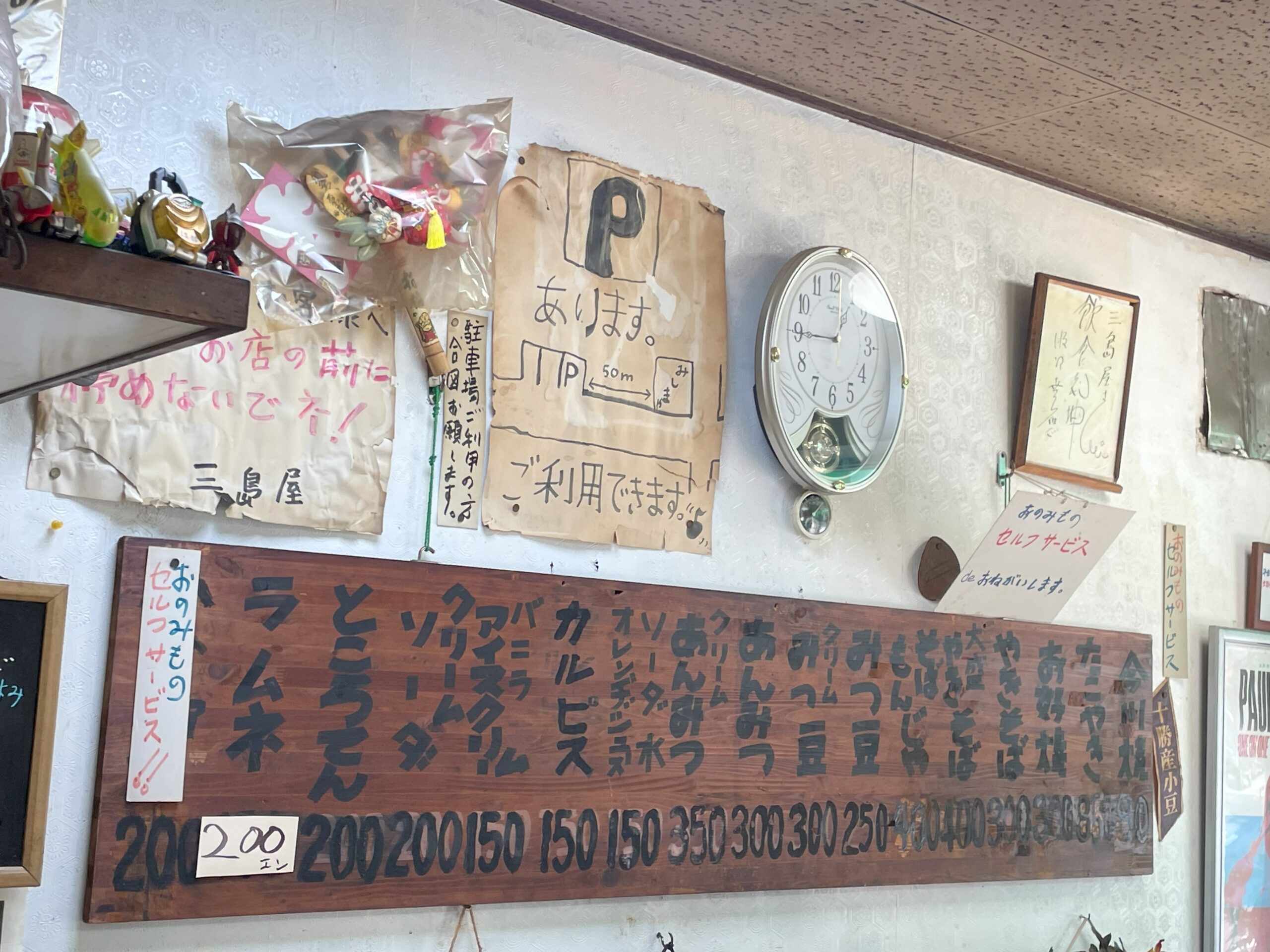 壁に掛けられた木製のメニュー板。手書きで「ラーメン」「今川焼き」「クリームソーダ」などが並んでいる。