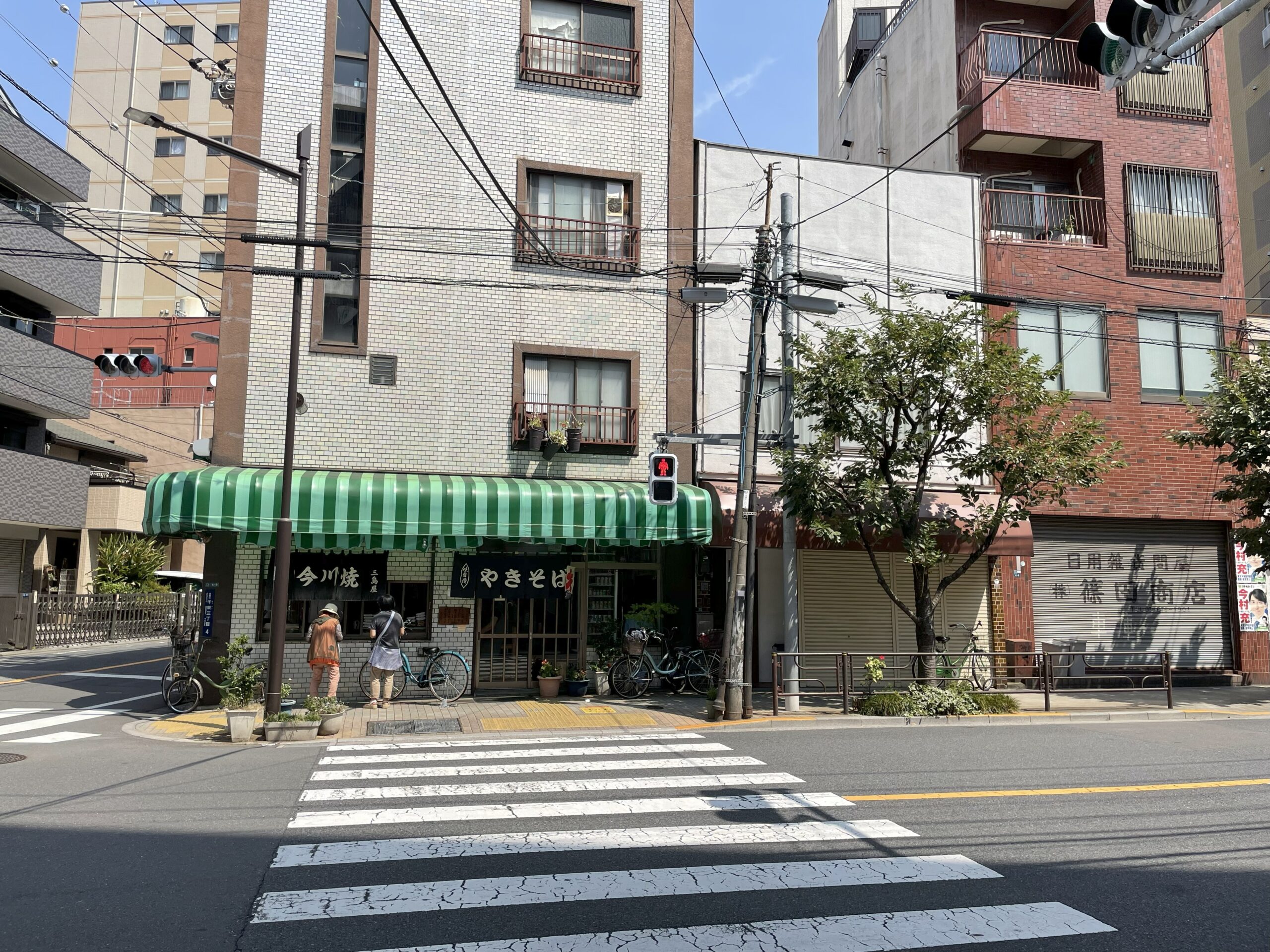 緑と白のストライプのテントが目印の三島屋さん。入口には「今川焼」「やきそば」と描かれた暖簾が掛かっている。