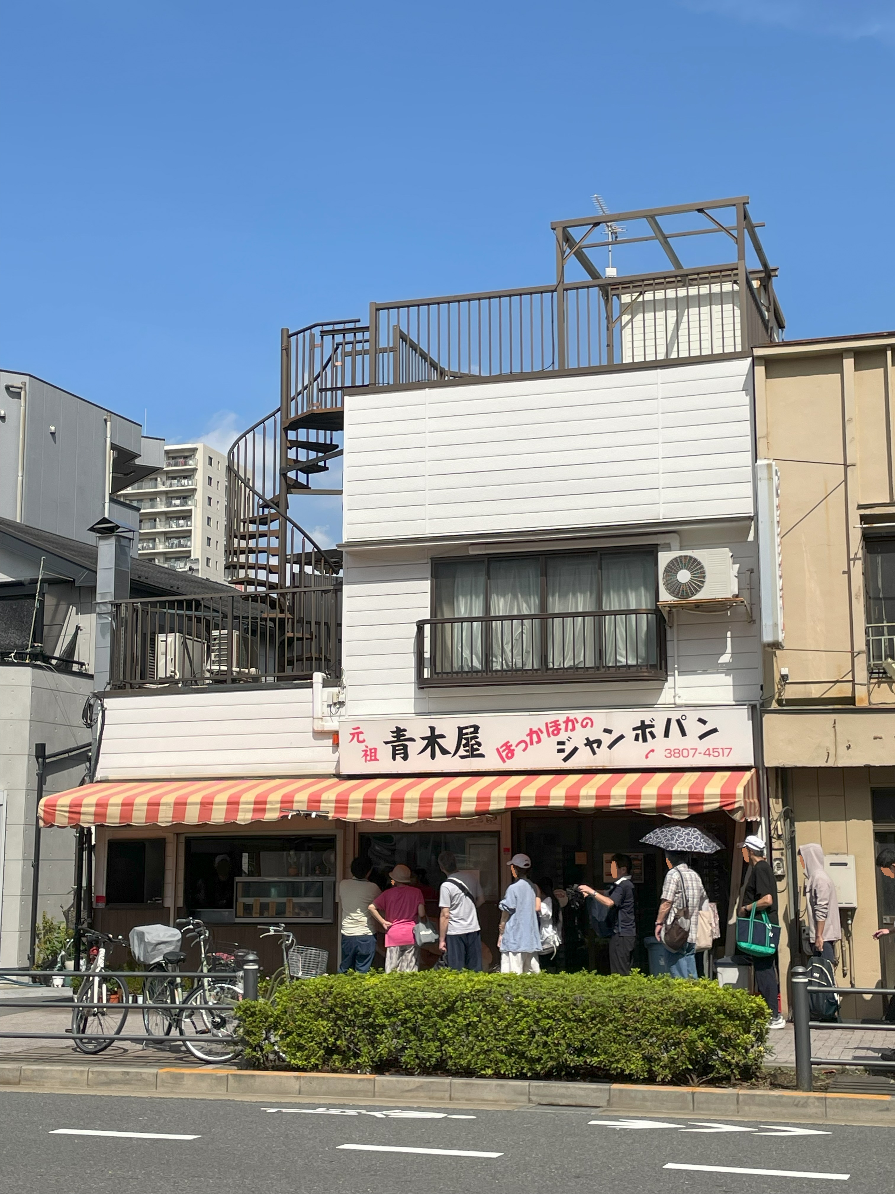 赤と黄色のテントが目印の「元祖・青木屋」さんの店舗前に並ぶ行列の様子。