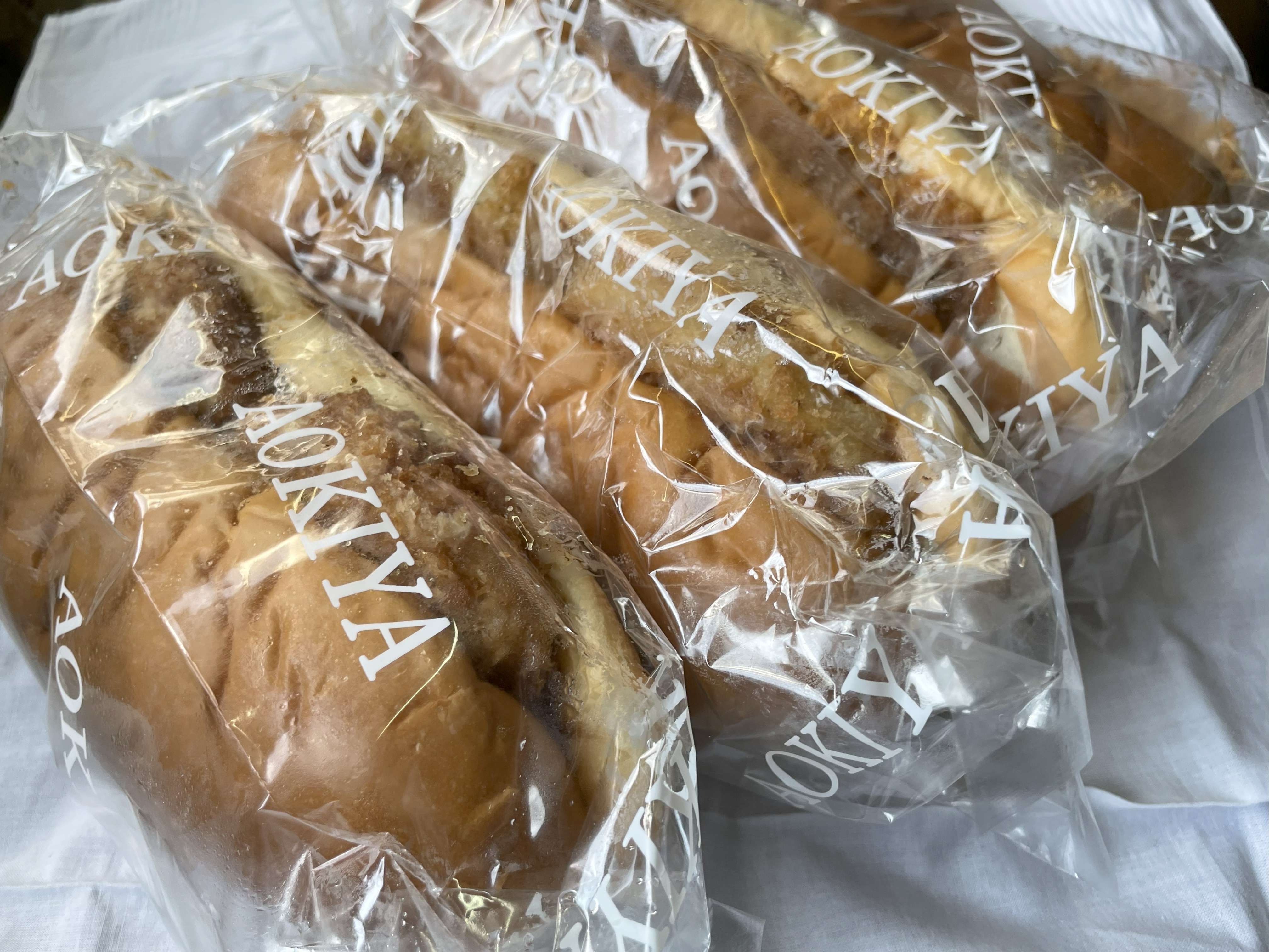 青木屋さんのジャンボパン「コロッケパン」「ハムカツパン」「メンチカツパン」「とんかつパン」が袋詰めで並んでいる様子。