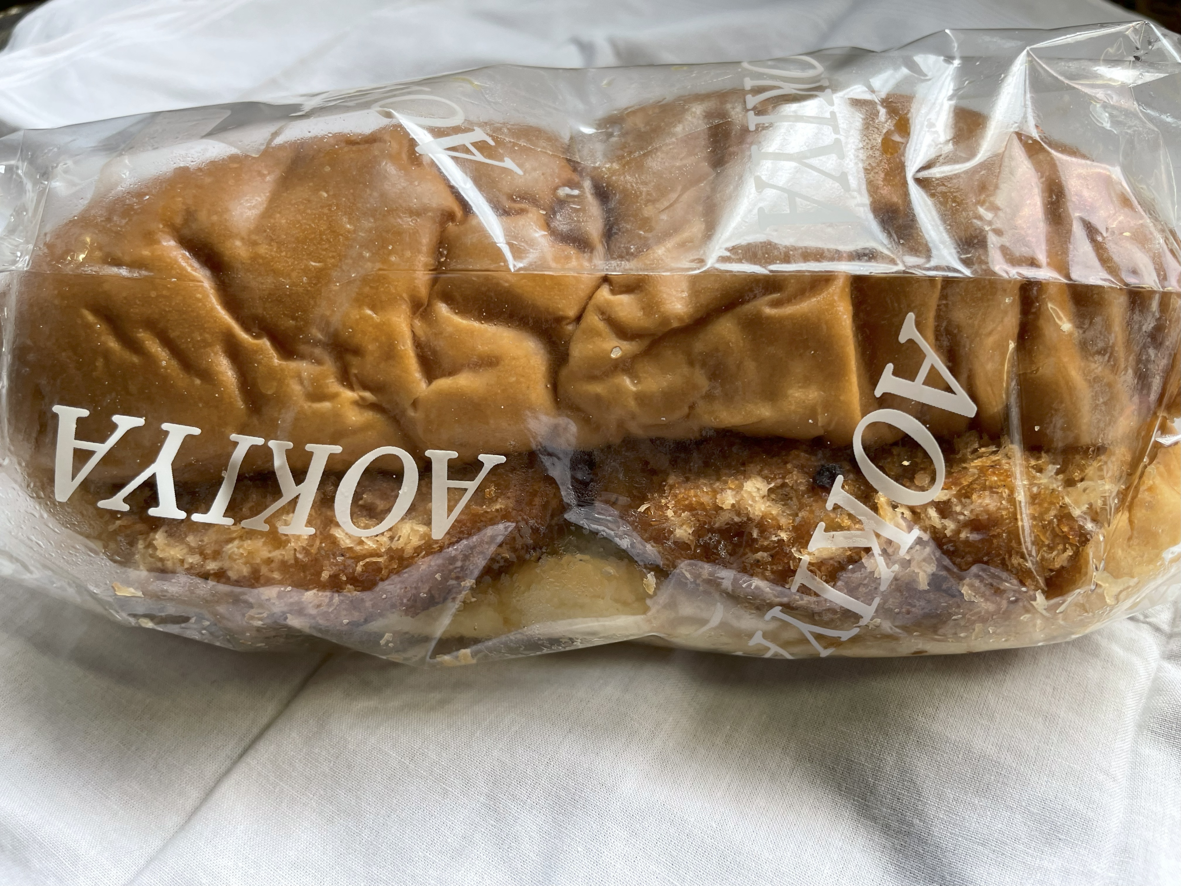 青木屋さんのメンチパン。粗めのパン粉で揚げられたメンチカツがパンからはみ出すように挟まれている。