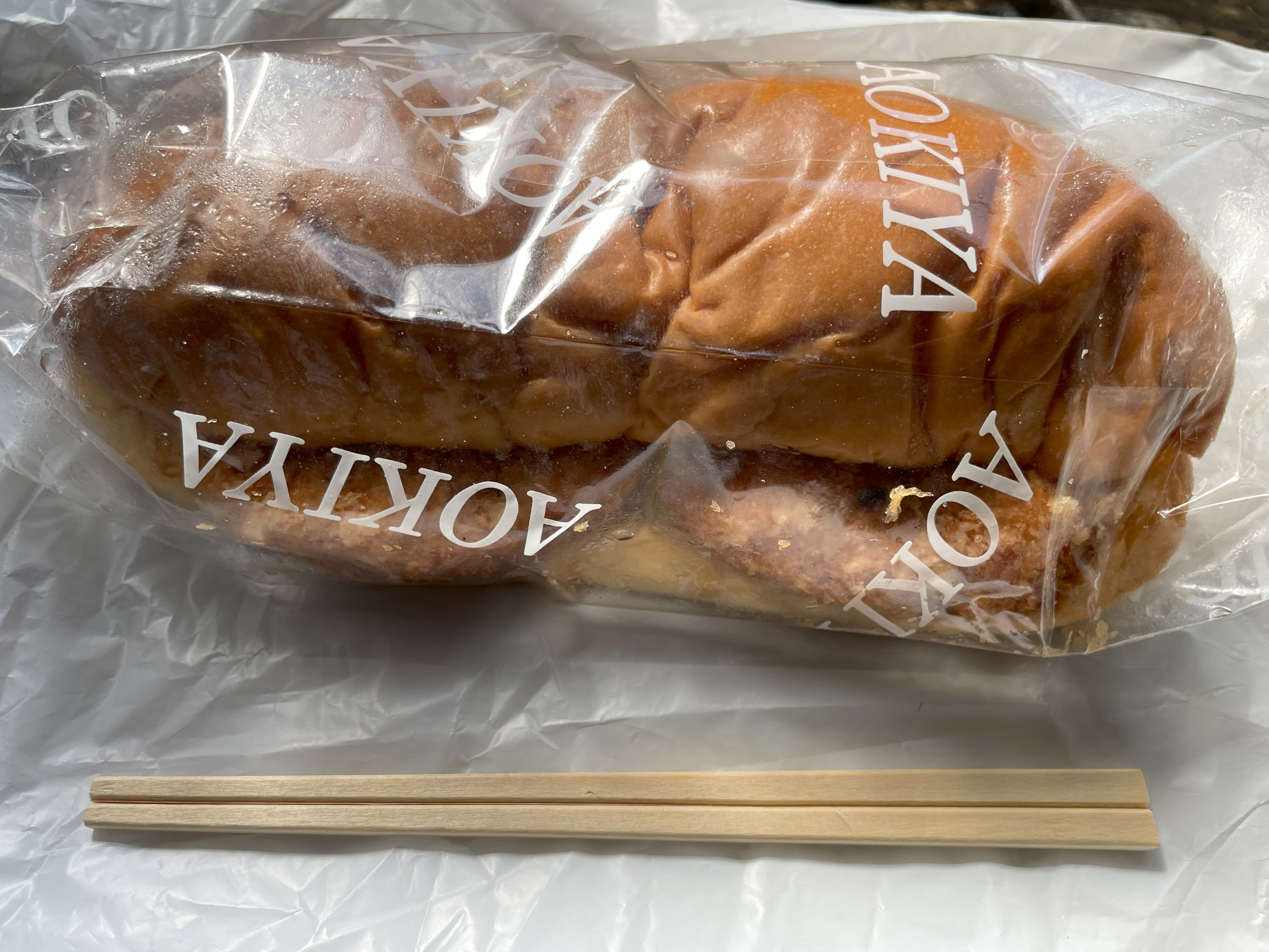 青木屋さんのジャンボパン1個と割り箸を並べて撮影した写真。パンのサイズ感がよくわかる。