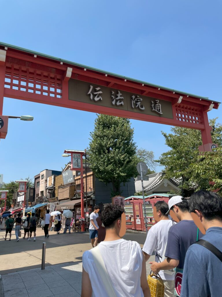 「伝通院通り」を行き交う人々。「伝通院通」の赤い看板が設置されている。