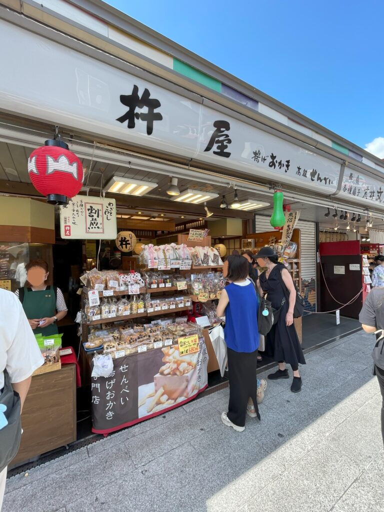 仲見世にある「おかき」「せんべい」の販売店。店頭に並んでいる商品を観光客が見ている。