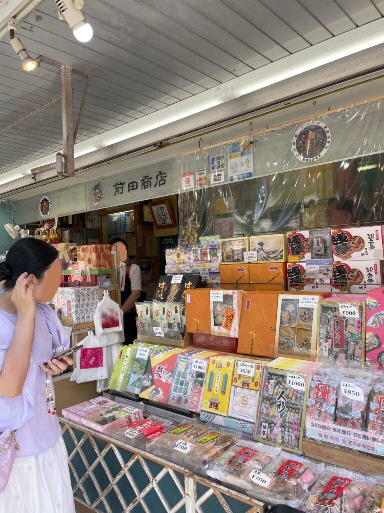 店頭に置かれた雷おこしなどの和菓子。観光客の女性が商品を見ている。