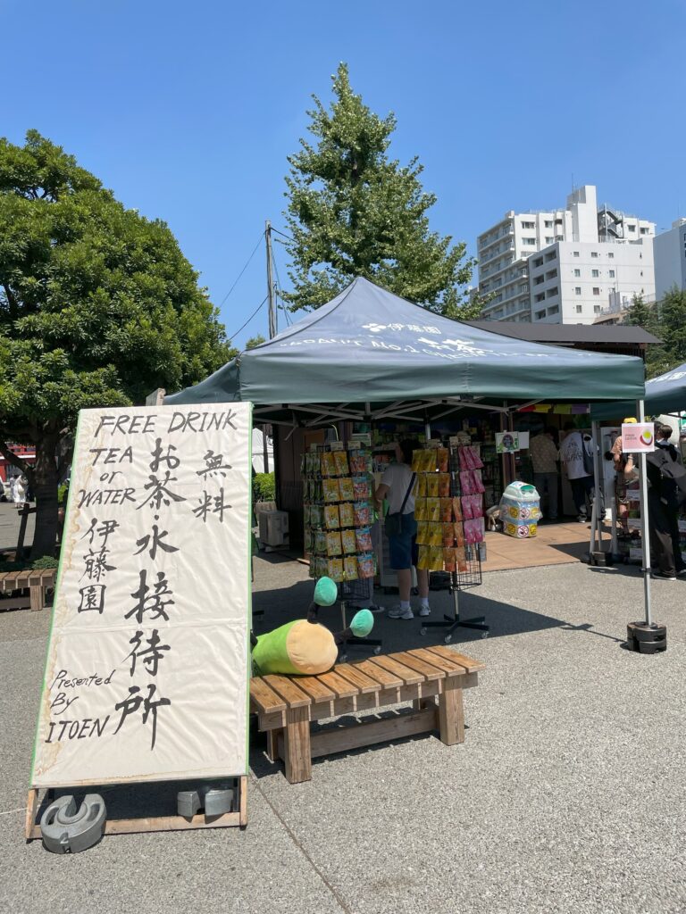 「お茶・水接待所」のベンチで、伊藤園さんのマスコットキャラクター「お～いお茶くん」が仰向けになって倒れている。
