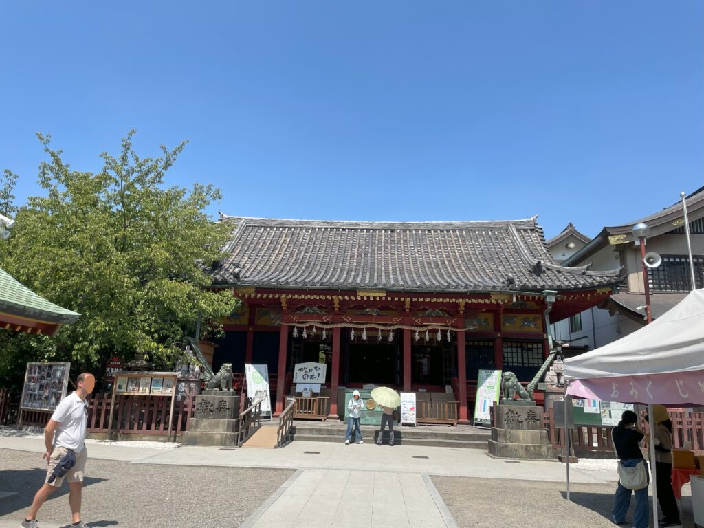 浅草神社の境内。ご神殿へ参拝する人、おみくじを引く人の様子。