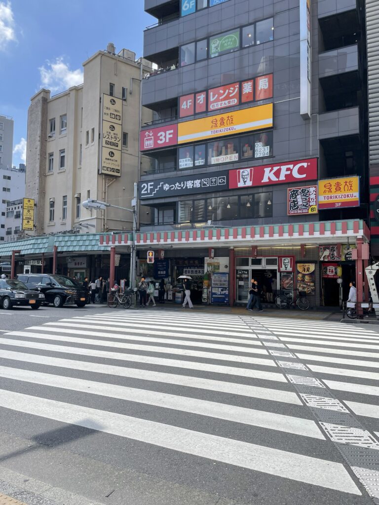 「馬道通り」の横断歩道。商業施設があり、車と人の往来している。