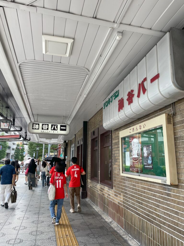 吾妻橋交差点の角にある「神谷バー」の周りを人々が歩いている。