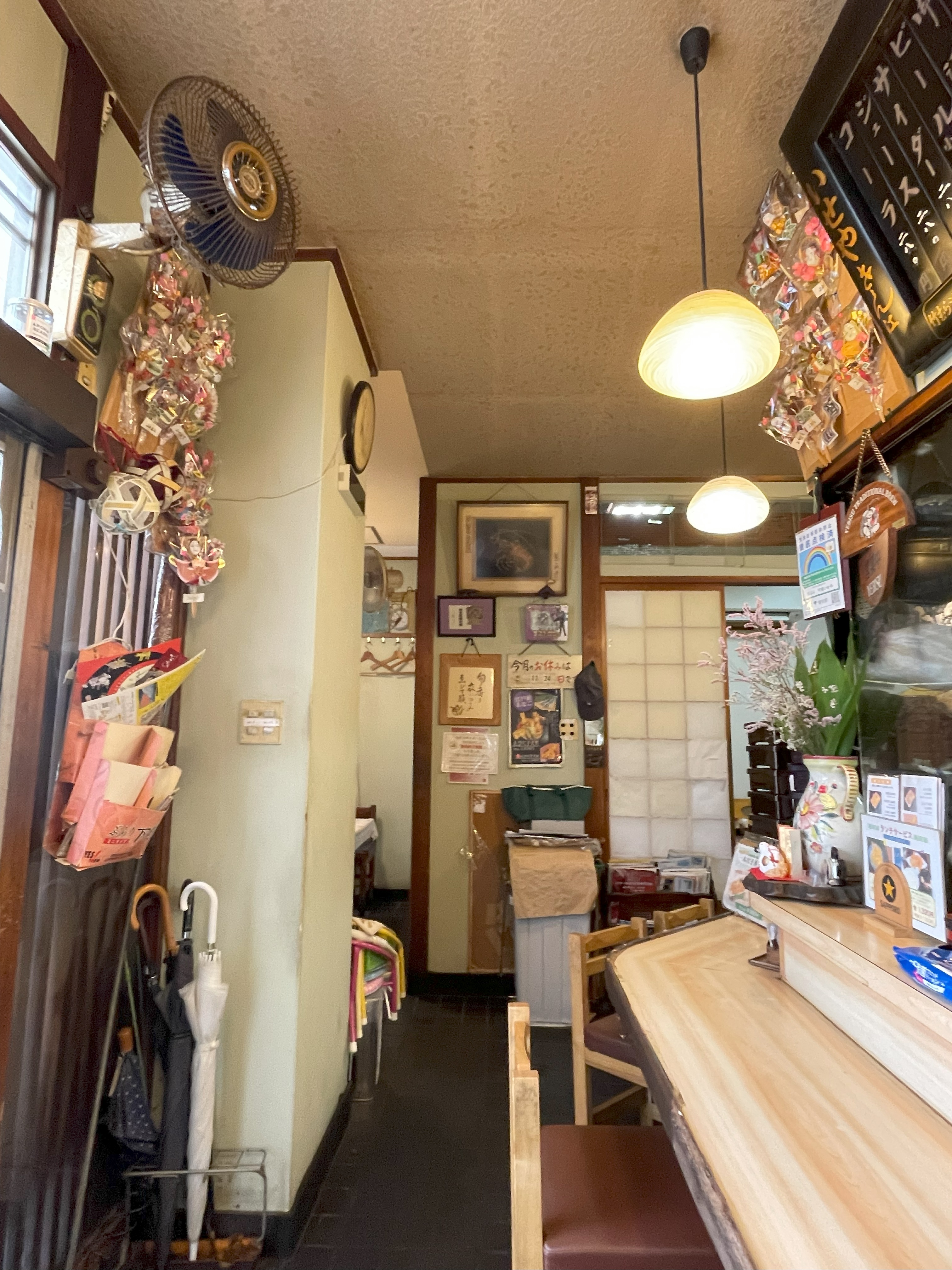 いせや千束の店内。木目のカウンターと招き猫、昭和の面影を感じる装飾。