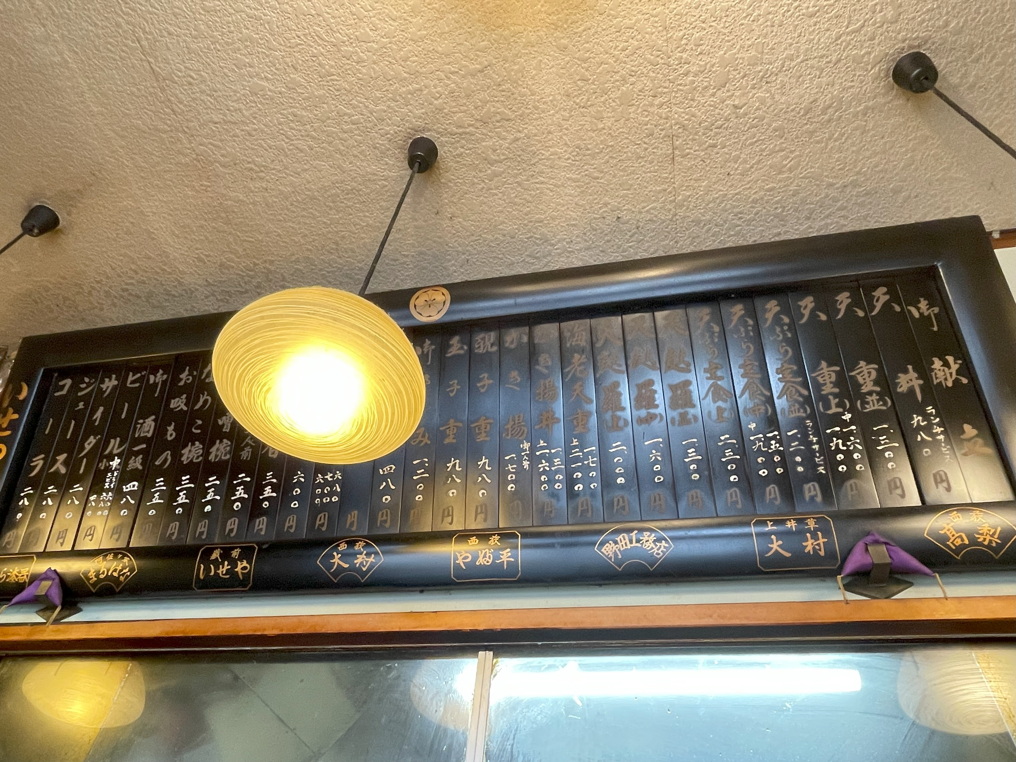 カウンター席の上に飾られた扁額のお品書き。