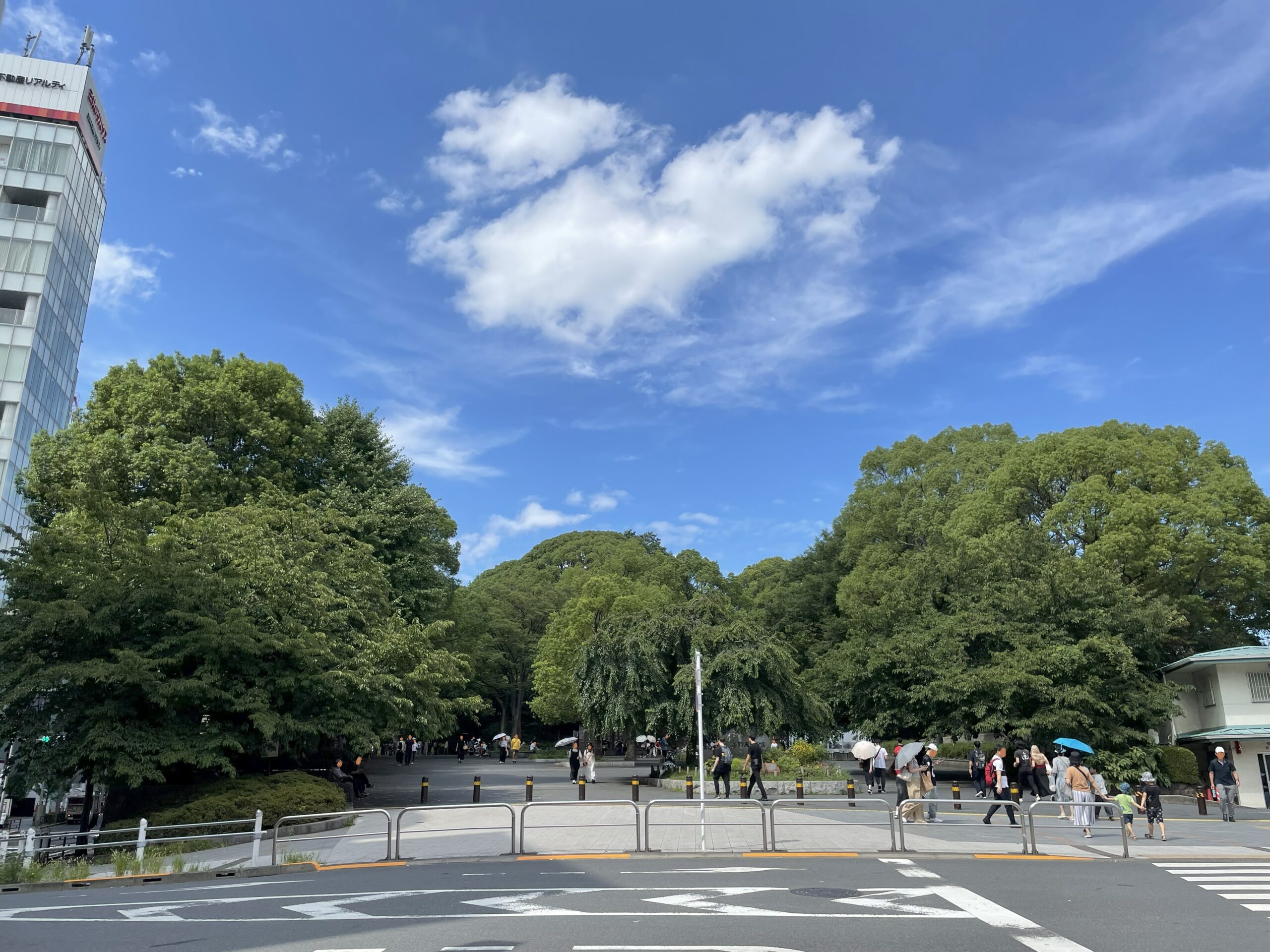 京成上野駅近くの上野公園の入口。夏の青空の下、人々が行きかっている。