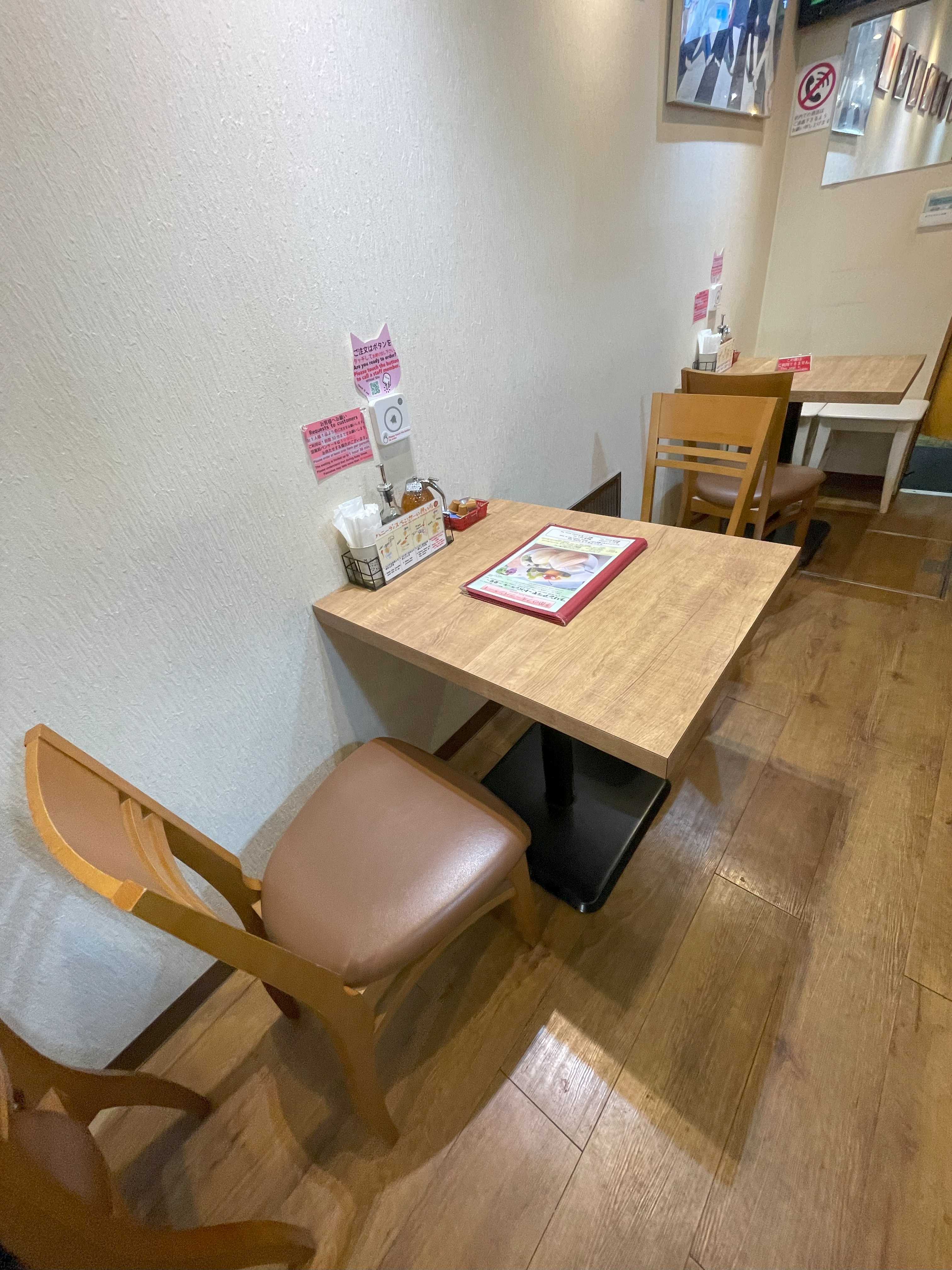 白壁に面したテーブル席とメニューが置かれた店内の様子。