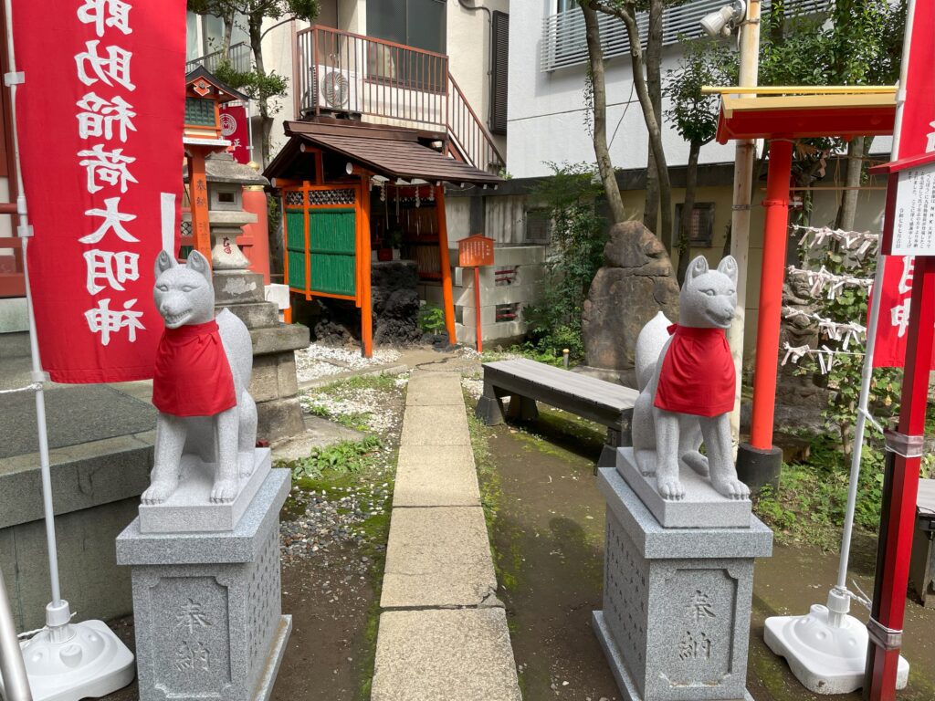 吉原神社の神狐様の像一対（赤い前掛け付き）。