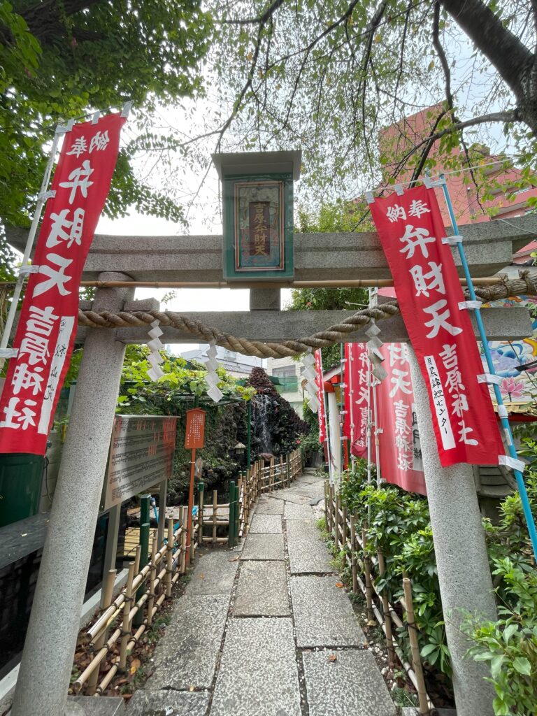 吉原弁財天様へ続く石畳と赤い幟、滝のような装飾。