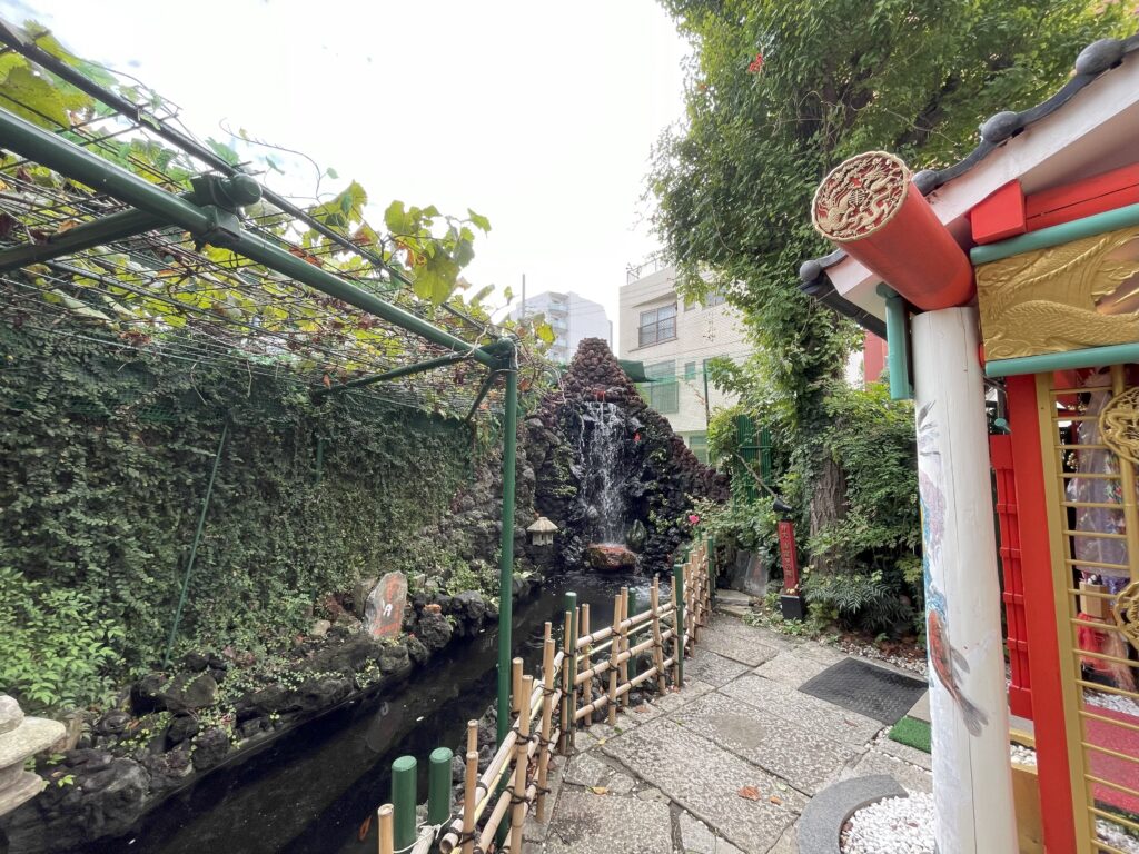 苔むした庭にある吉原観音様の滝と祠の全景。
