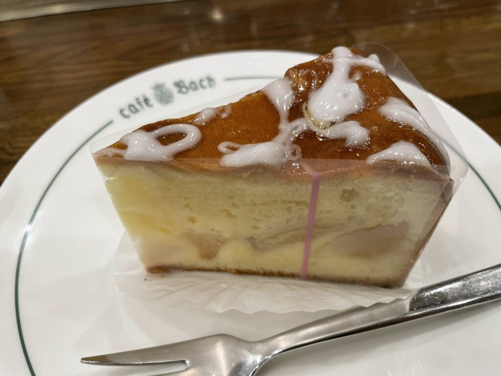 カフェ・バッハさんの昔風りんごのケーキ。白いアイシングがかかった、しっとり生地と煮りんごが見えるケーキの断面。