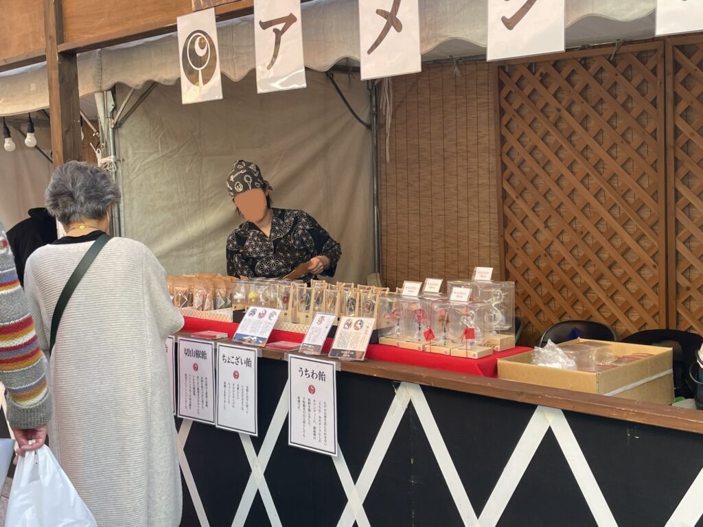 「妙見堂」の前に、あめ細工の屋台がある。