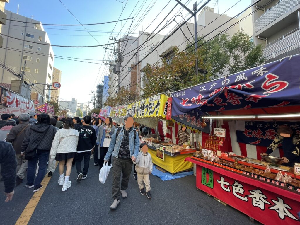 「酉の市」の屋台を眺めながら、たくさんの参拝者が歩いている。