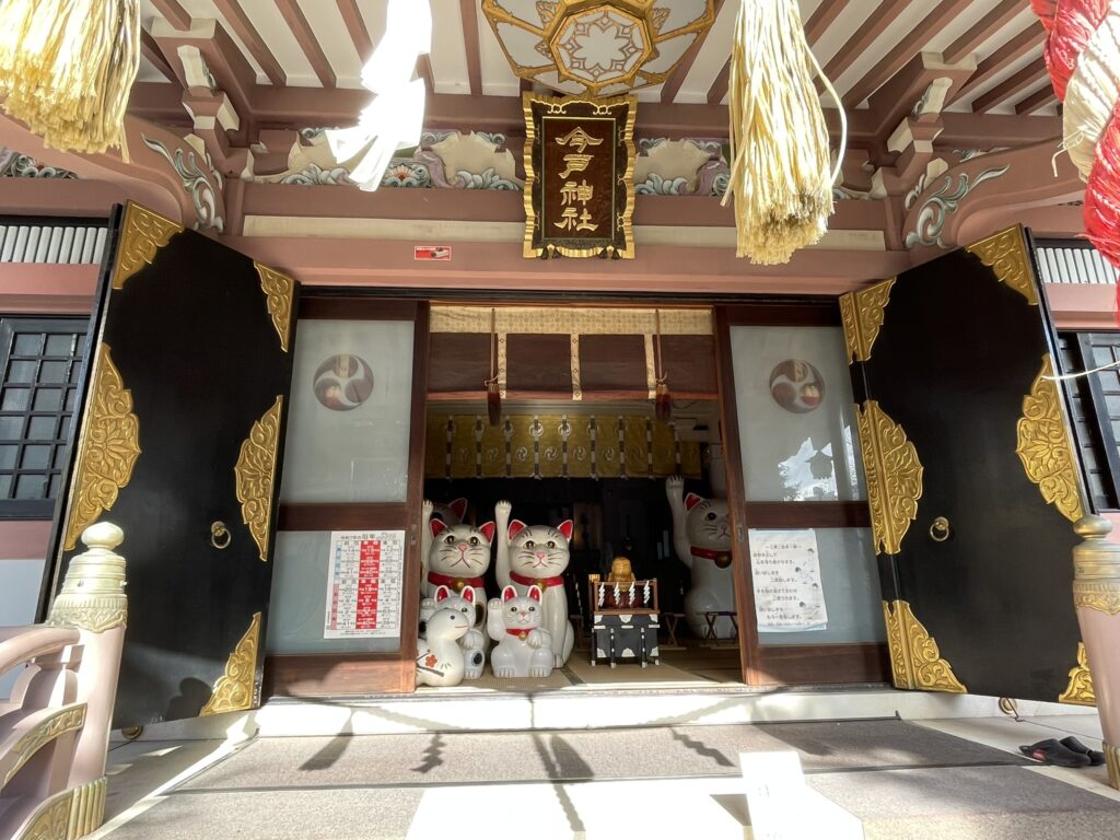 今戸神社の拝殿正面。扉の奥には、七福神の福禄寿（ふくろくじゅ）や干支の蛇、そして、大小さまざまな招き猫が並び、縁結びの神社らしい穏やかな雰囲気が広がっている。