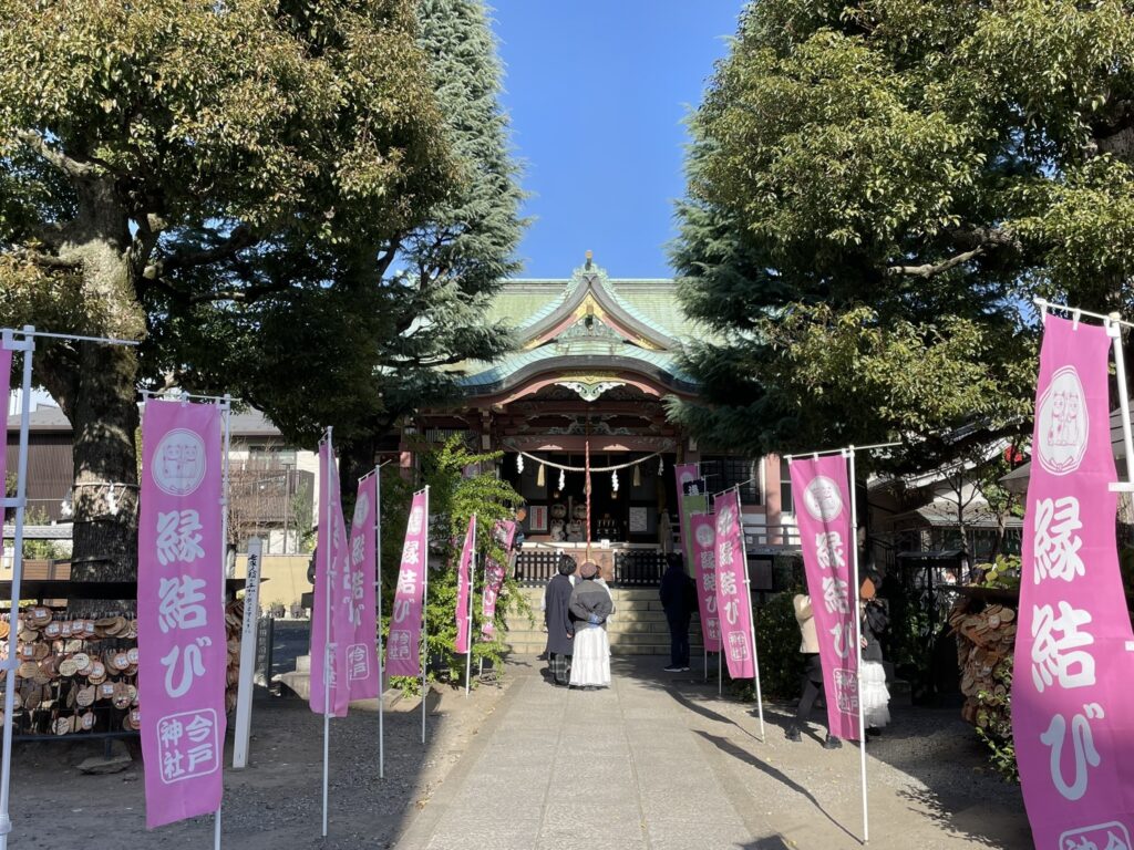 今戸神社の拝殿正面。両脇に「縁結び」と書かれた桃色の幟が並び、その奥に拝殿が見える。