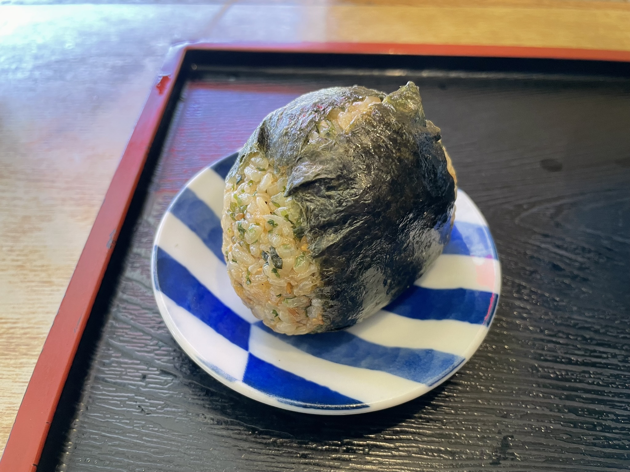 めん処おばたさんの包まれたラップを外した「悪魔のおにぎり」の写真。