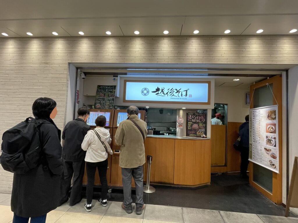 東京駅地下街にある越後そばさんの券売機に並ぶ来店客。