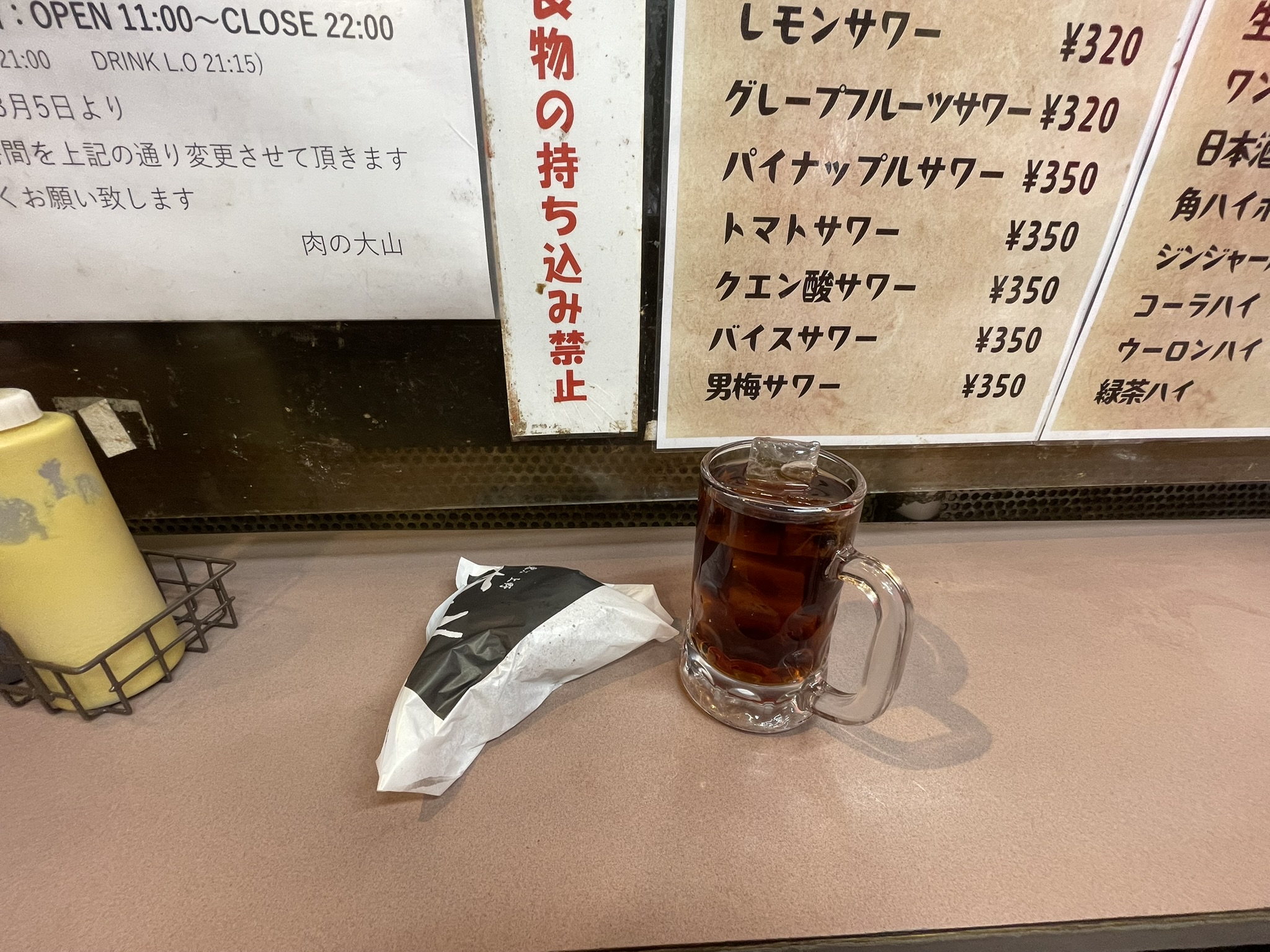 肉の大山さんのロゴが印刷された袋と「ウーロン茶（ソフトドリンク）」が入ったジョッキ。