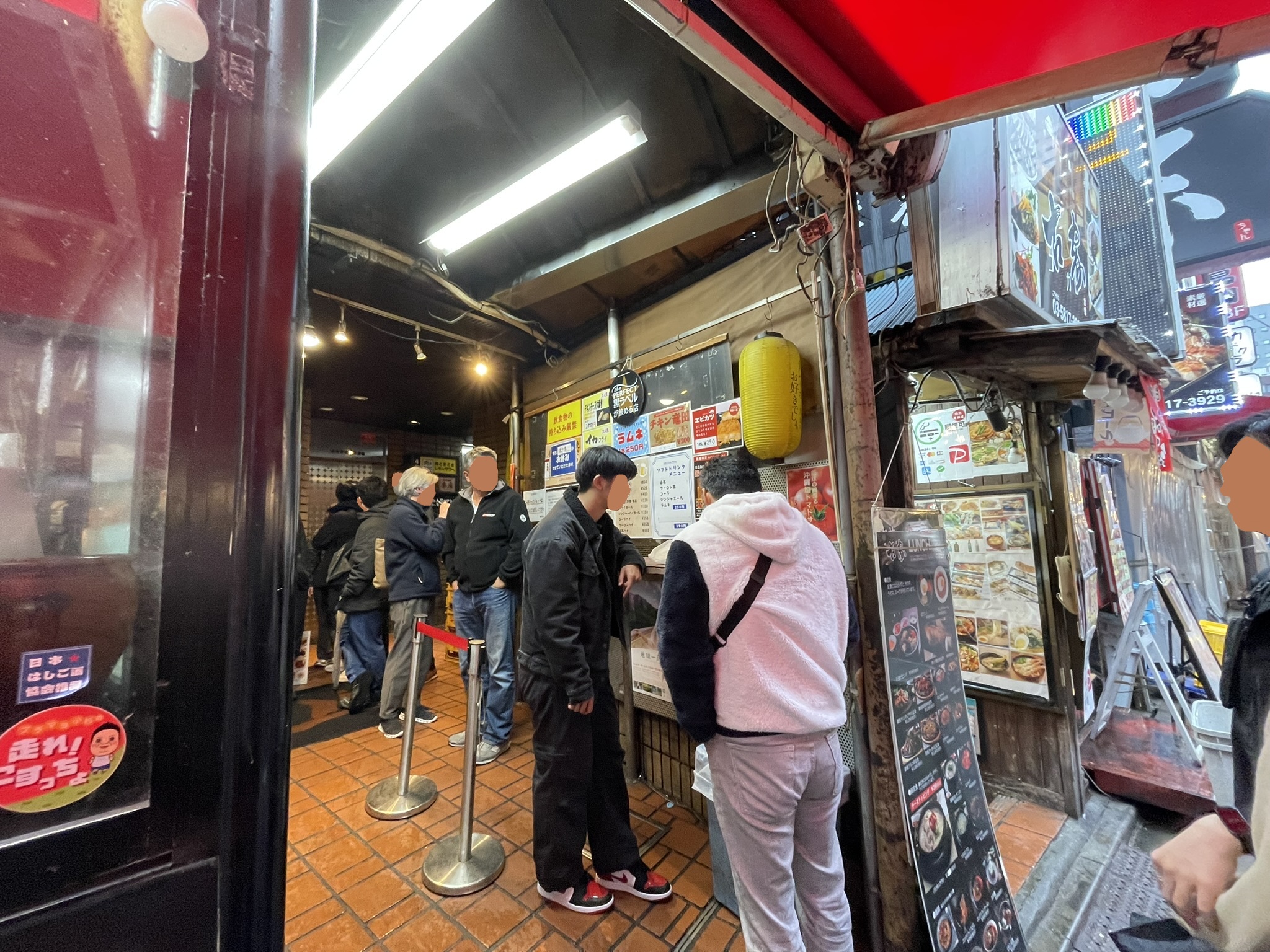 通路をはさんだ後ろのカウンターで食事をする人々。