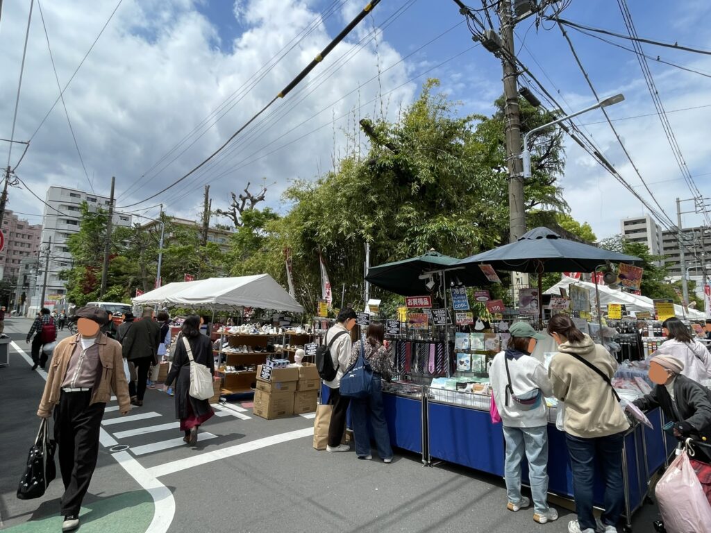 「お買得品」の看板が並ぶ雑貨・日用品コーナー。ネクタイ、マスクなど多様な商品が展開され、靴以外の出店も多彩であることが見て取れる。