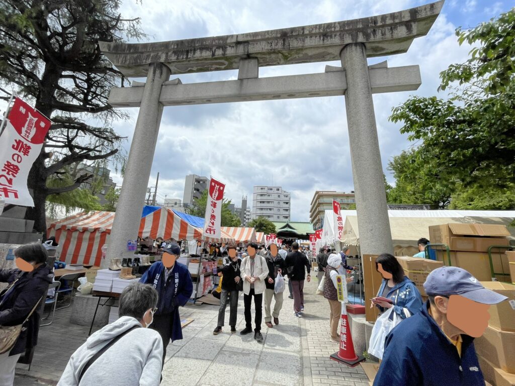 玉姫稲荷神社の大鳥居をくぐると、紅白のテントと「靴の祭り市」の幟が迎えてくれる。参道の両脇に出店が並び、普段の静かな境内とは打って変わった祭りの空気が漂う。