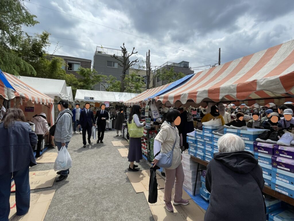 紅白テントが連なる境内通路は、多くの来場者でにぎわう。スーツ姿の参拝者の姿も見られ、老若男女が集う「こんこん靴市」ならではの光景だ。