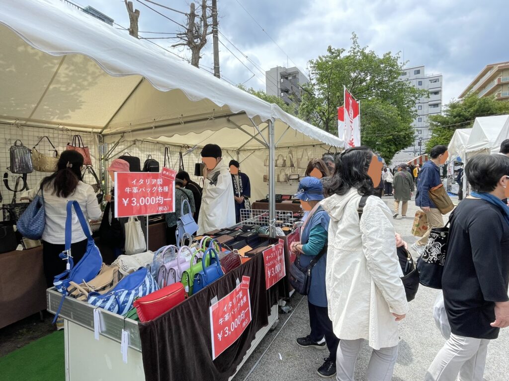 「イタリア製牛革バッグ各種 ¥3,000均一」の赤い看板が鮮やかなバッグコーナー。色とりどりの革バッグを手に取る来場者の姿が、靴市に財布やバッグなどの皮革製品が揃うことを改めて伝えてくれる。