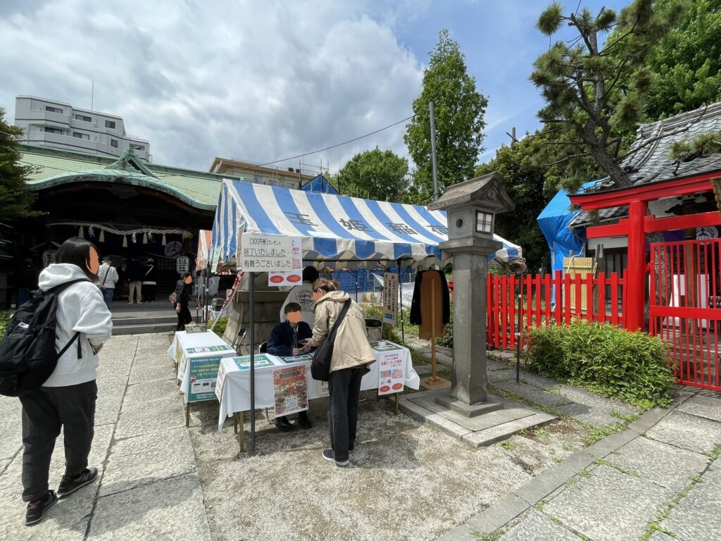 玉姫稲荷神社の社殿を背景に設けられた案内ブース。「¥300円券プレゼント 終了いたしました」の貼り紙が、来場者の多さを物語っている。