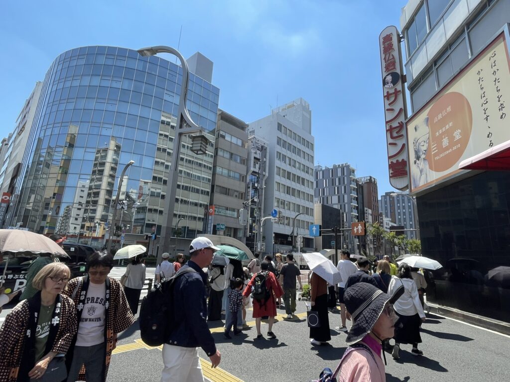 田原町に日傘をさした観光客や法被を着た氏子たちがいます。
