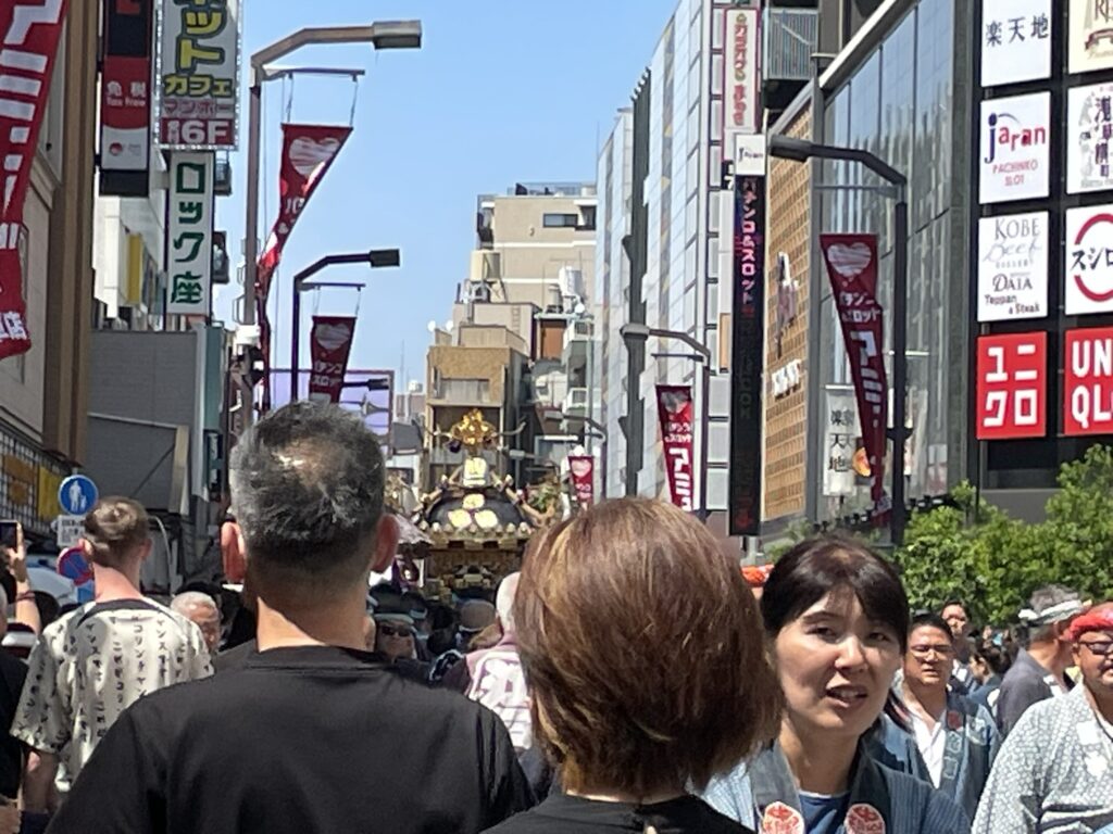 六区ブロードウェイを行くお神輿と、それを取り囲む観光客・氏子たち。