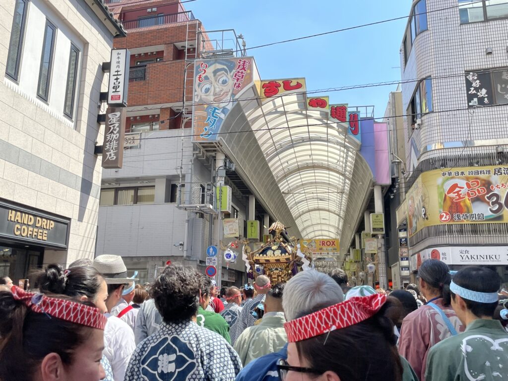 すしや通りのアーケードを進む神輿行列。提灯と神輿が織りなす、祭りの情景です。