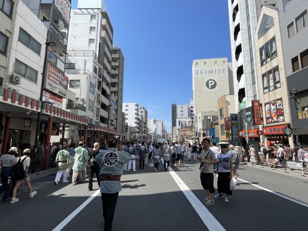 馬道通りを歩く人々。交通規制の中、お神輿の巡行に合わせて動く観客たち。