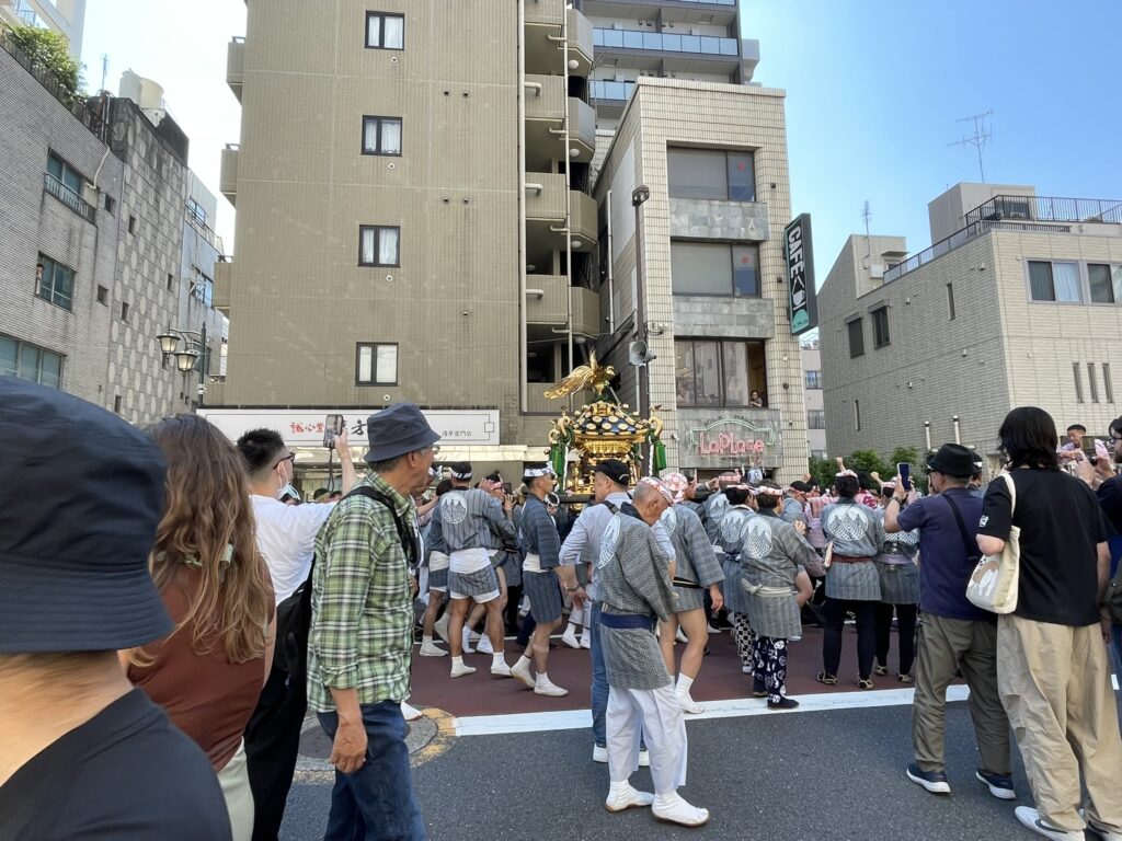 担ぎ手に囲まれながら進む町内神輿。沿道の声援を受けて、力強く進みます。