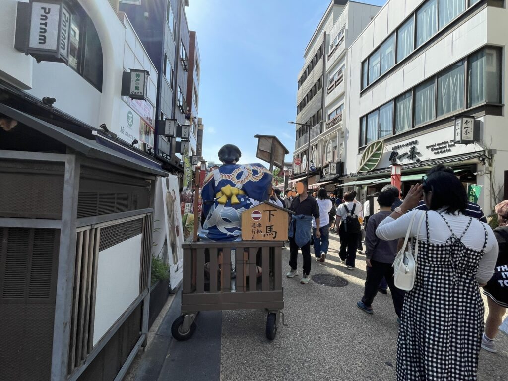 浅草の参道を練り歩く「白波五人男」の人形山車と見物客。