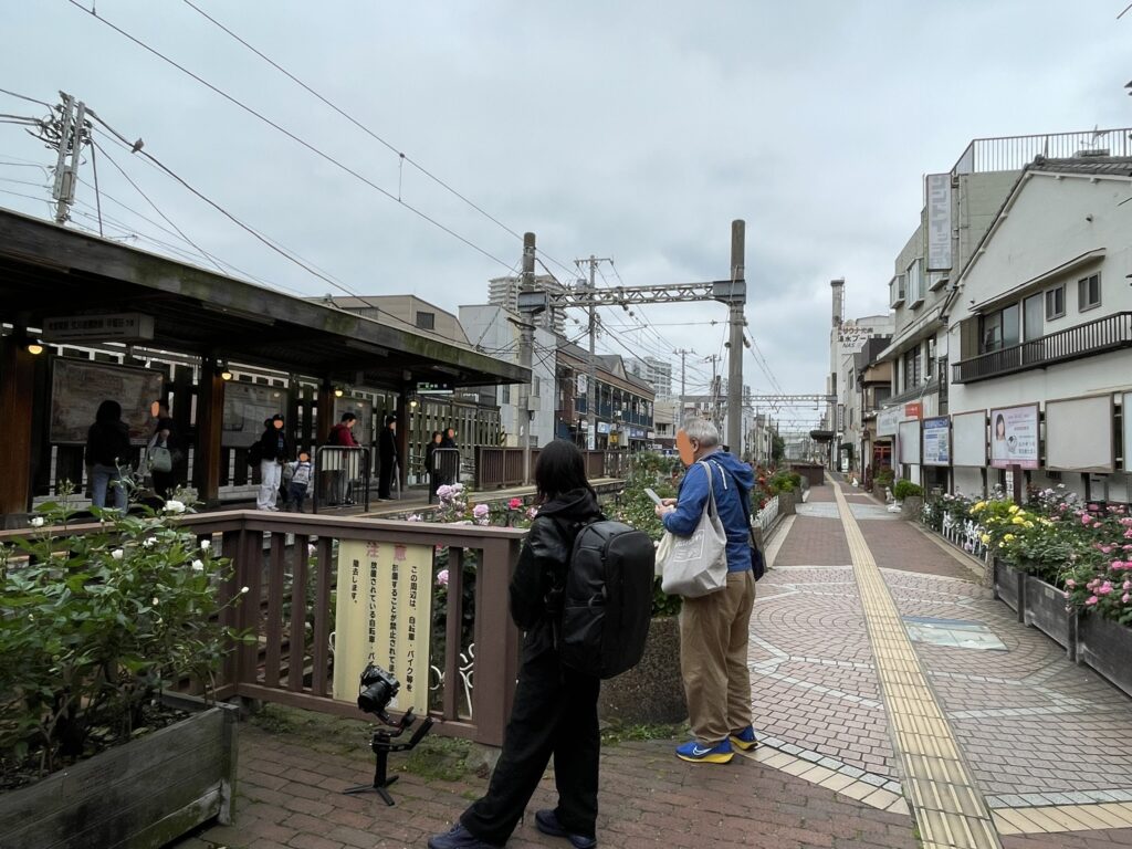 三ノ輪橋停留場の全体風景。カメラを構えた撮影者たちと、沿道に続くバラ花壇。