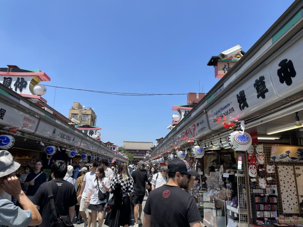 青空の下、人があふれる仲見世通り。遠くに宝蔵門が見える。
