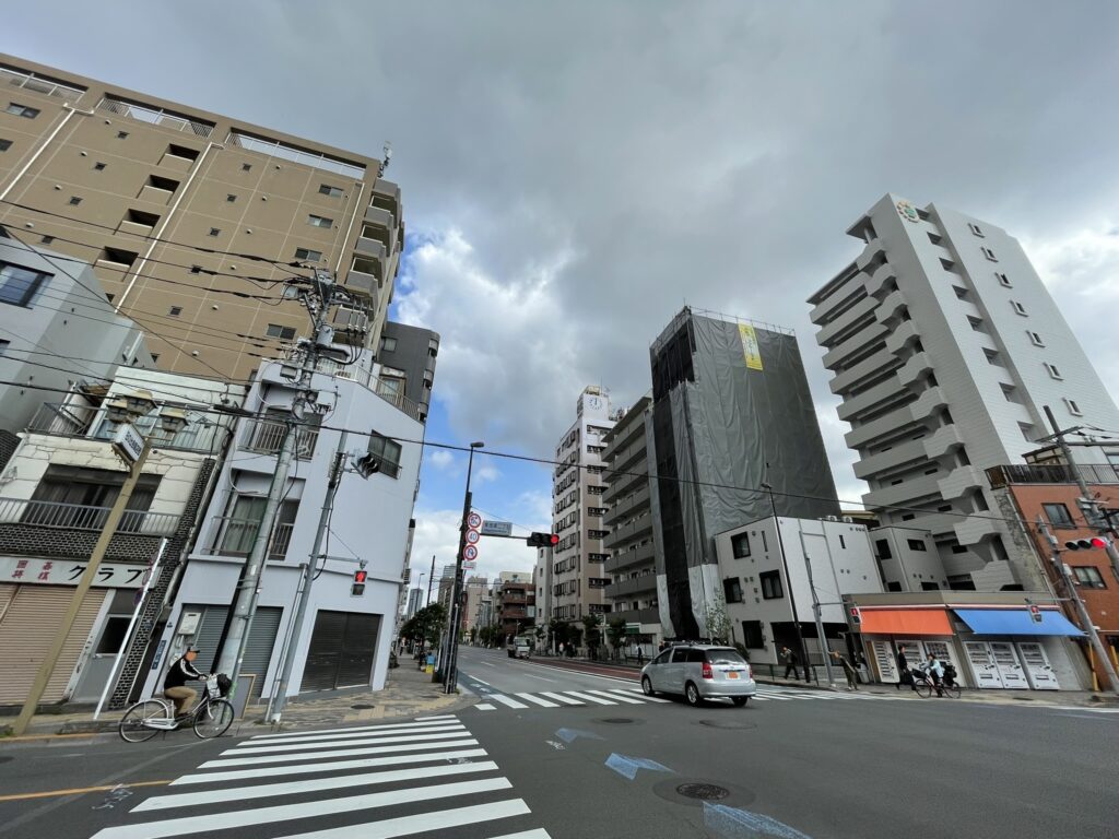 新旧の建物が混在する山谷の交差点。再開発が進む中にも、昭和の面影を残す街並みが残っている。朝の空に広がる雲が、この街の今を映し出す。