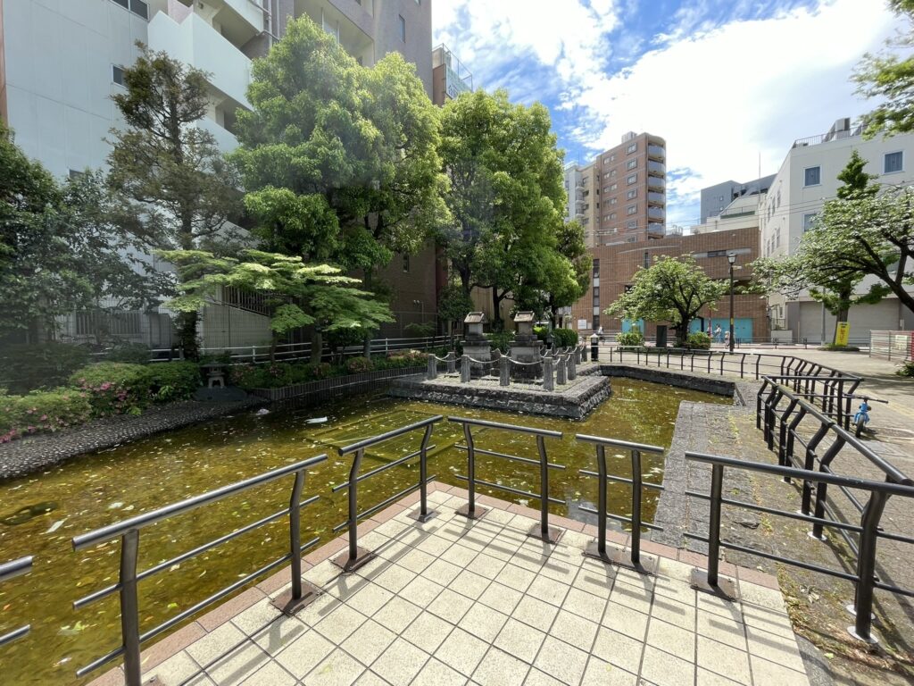 人工池の全景。柳の木が水面にしだれ、かつて旅人が身を投じたという伝説の池の面影をわずかに残している。